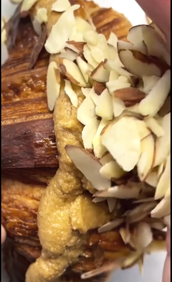 Once cooled (or for day-old croissants), slice horizontally. Pipe/spread a generous layer (~2 tbsp) of frangipane inside, close, spread a thin layer on top, cover with sliced almonds, re-bake briefly to toast almonds, and dust with powdered sugar.