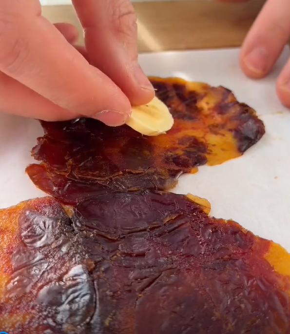 Drizzle or spread natural peanut butter or tahini evenly over the date base. Arrange the thin banana slices in neat rows on top.