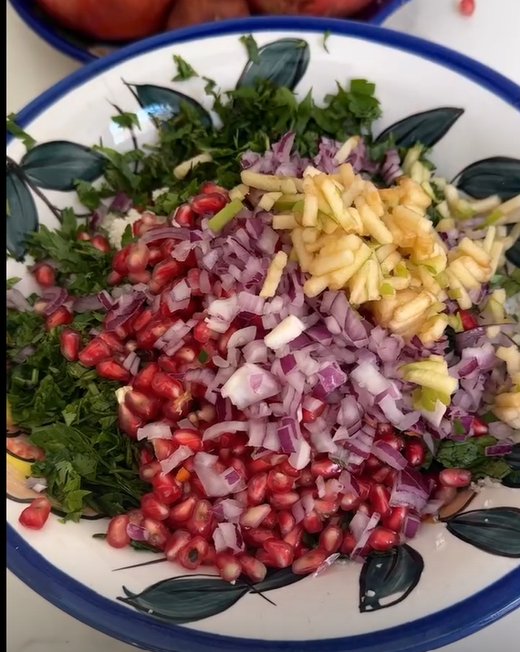 Add the julienned green apple, fresh pomegranate arils, dried cranberries, and finely chopped herbs to the cauliflower.