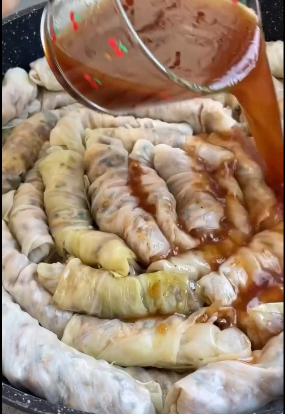 Layer leftover leaves at bottom of pot. Pack rolls tightly, pour tomato sauce mixture over top, place an inverted plate to hold rolls in place, cover, and simmer for 50–60 minutes.