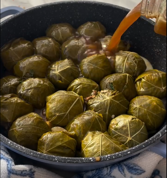 Place leaf flat (shiny side down), add 1 tsp filling near stem, fold sides, and roll tightly.