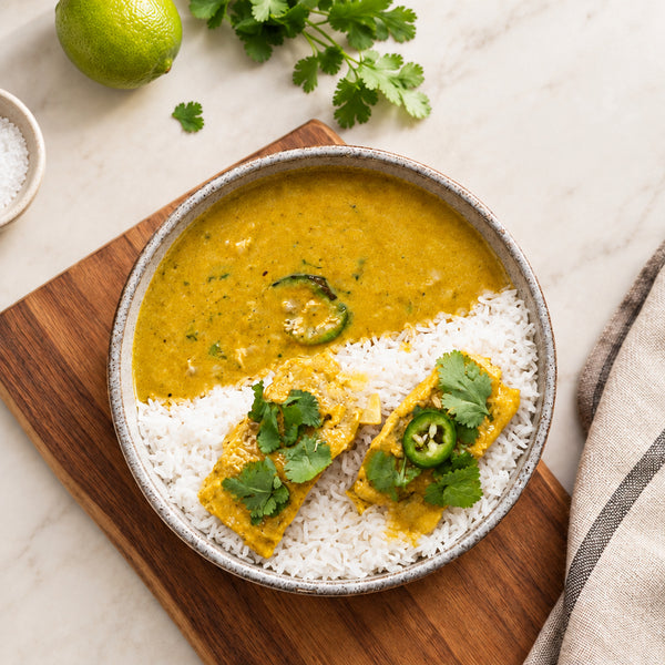 Squeeze fresh lime juice, garnish with cilantro and toasted nuts, and serve hot over coconut rice.