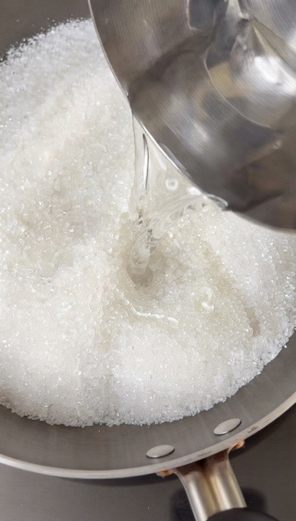 Pouring liquid directly over the base layer of sugar in the pan.