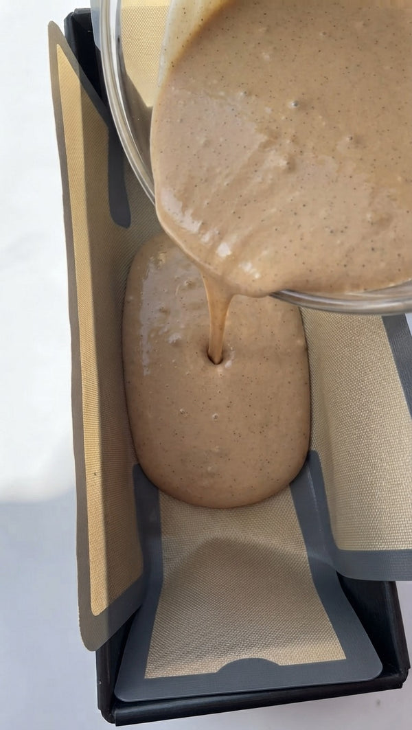 Pour the smooth, rich cinnamon-infused batter smoothly from the mixing bowl into the prepared, lined loaf pan to form the base.