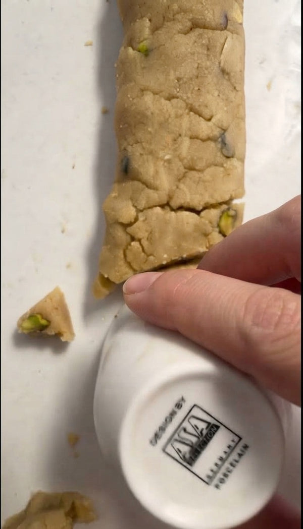 Use a round cutter or cup rim to stamp out distinct crescent-shaped cookies from the log.