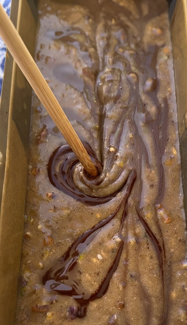Transfer and pour the prepared, nut-infused batter evenly into a lined loaf baking pan.