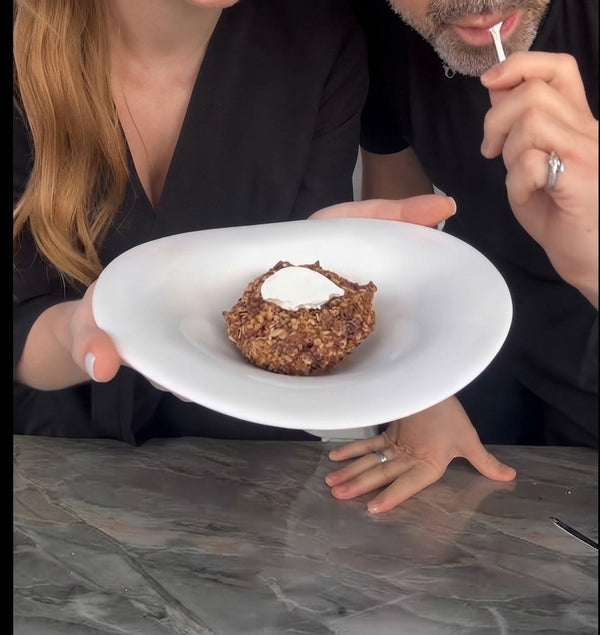 Serve the finished, beautifully plated baked dessert on a white dish with a dollop of cream on top.