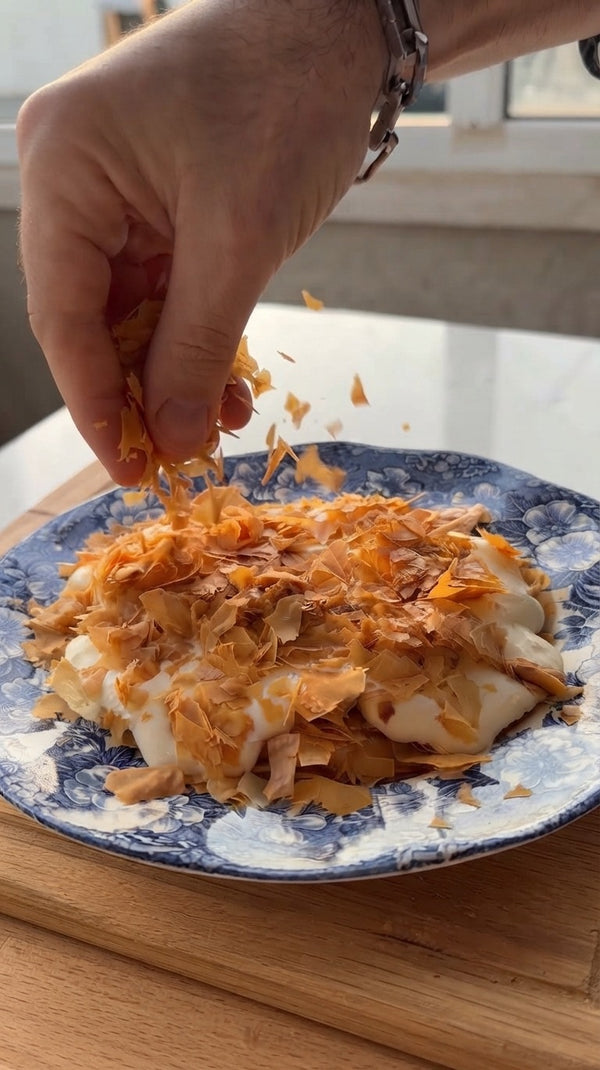 The prepared mixture is placed onto a decorative plate. A final, abundant topping of the crispy pastry shards is sprinkled over the top.