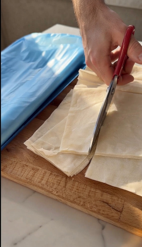 The unwrapped dough block is then cut into smaller, manageable rectangles using kitchen shears.