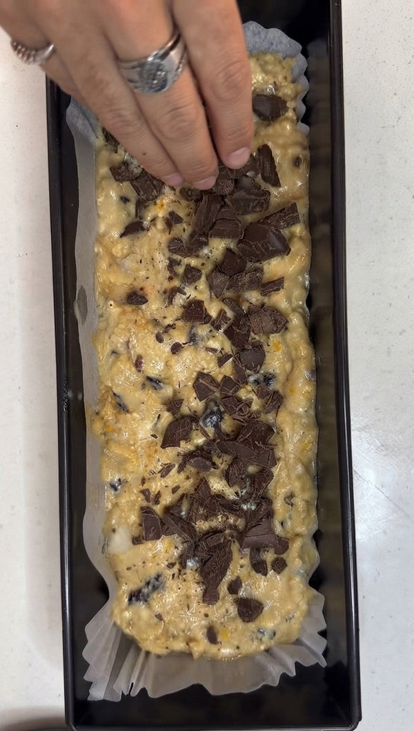 Scatter chopped dark chocolate pieces evenly across the surface of the loaf batter.