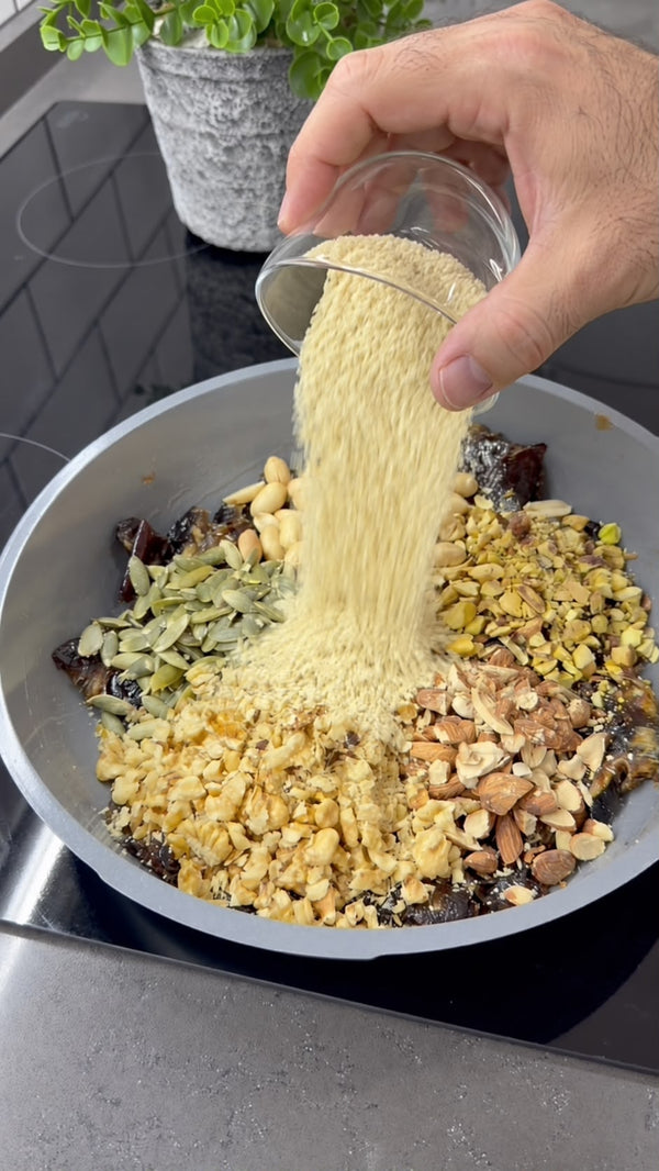 In a mixing bowl, combine date paste, ground walnuts, ground pistachios, and shredded coconut. Knead until a uniform, dense dough forms.