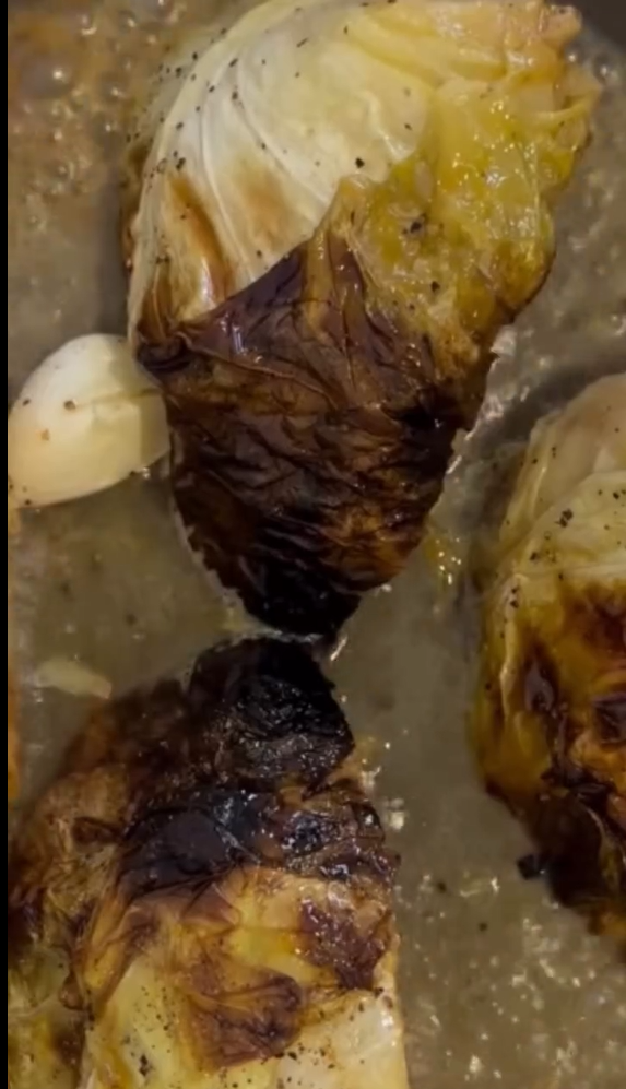 Initial slow roast in oven. Preheat oven to 140°C (285°F). Brush the thick cabbage slice with softened butter, olive oil, salt, and pepper. Wrap tightly in parchment paper and bake for 35 minutes. Remove parchment, increase temperature to 160°C (320°F), and roast for another 10 minutes until slightly charred along the edges.