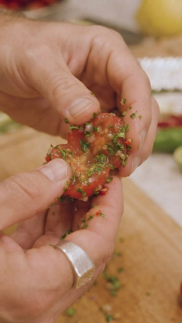 Hand-chop the sea bream fillets into coarse ½ cm pieces. Mix thoroughly with cilantro, green onion, chili, garlic, olive oil, salt, and pepper. Firmly pack the fish mix into the halved Tinkerbell peppers so the filling stays secured.