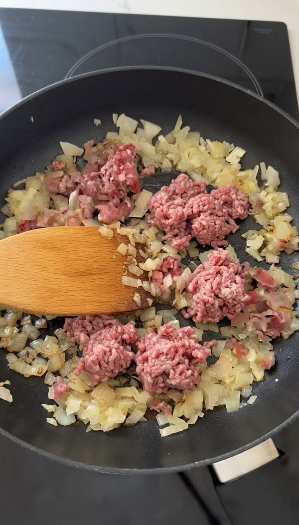Add the ground beef (and lamb fat mixture) to the skillet. Sear and break it apart with a wooden spoon, letting the juices render and release rich aromas.