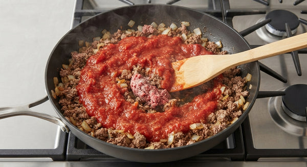Add sweet paprika, hot paprika, salt, black pepper, tomato paste, and whole peeled tomatoes. Crush the tomatoes gently into the skillet and let the sauce simmer on medium-low heat until thickened and reduced.