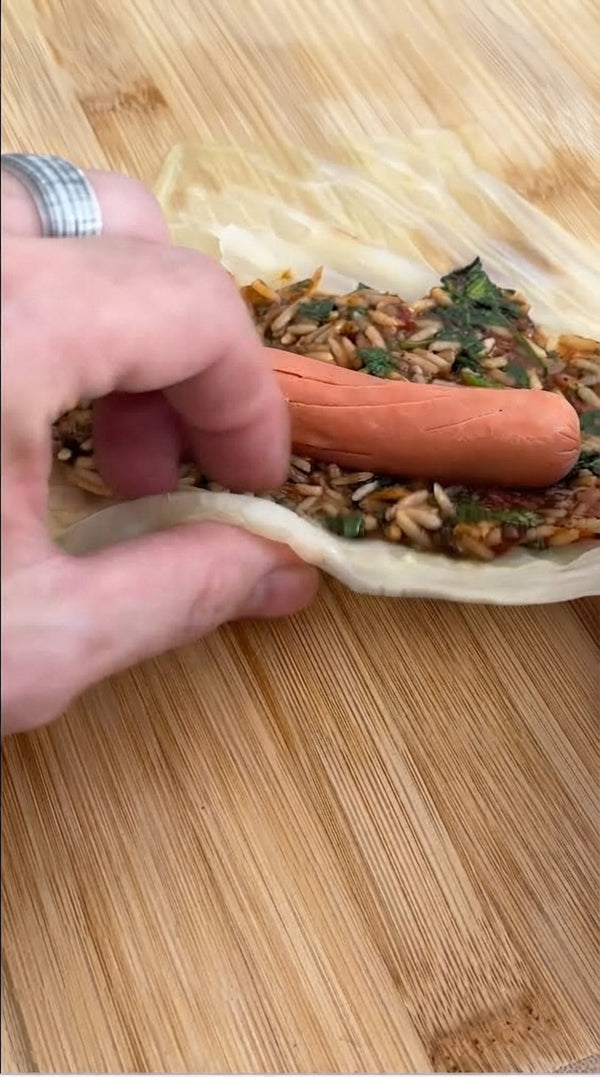 Lay each leaf flat, remove tough central rib, place filling, fold edges, and roll tightly.