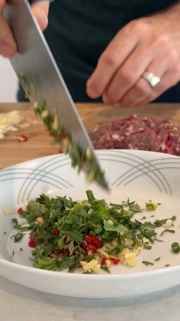 Sauté grated onions in olive oil until golden. Add sage, garlic, chili, red wine, Ras el Hanout, beef stock, and silan. Place date balls into sauce, cover with foil, and bake at 180°C (350°F) for 25 minutes. Uncover to brown.