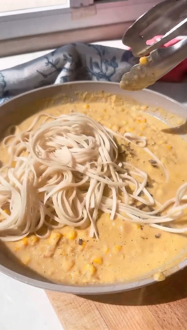 Toss the cooked noodles directly into the corn-coconut sauce. Garnish with chopped green onions, fresh cilantro, and chili flakes.
