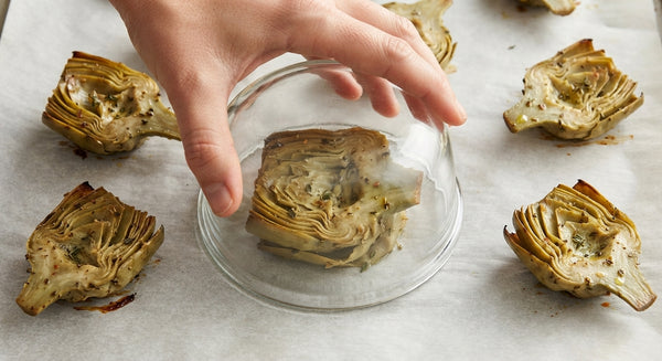 Scatter mounds of grated Parmesan on parchment paper. Place artichokes flat-side down on cheese mounds and smash flat using the bottom of a glass.