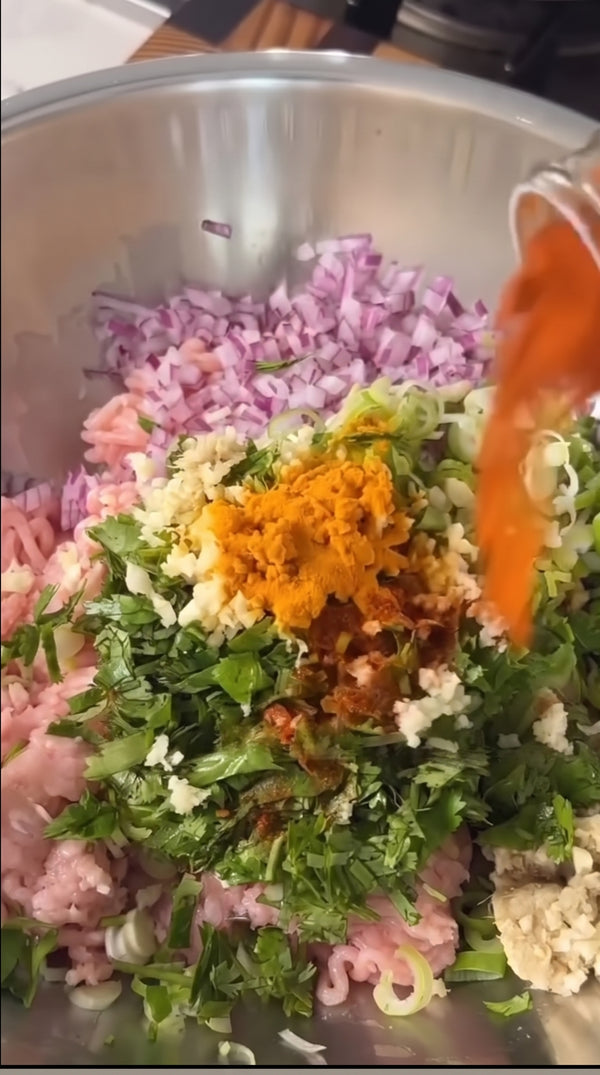 Курица с насыщенным пряным вкусом. В большой миске смешайте куриный фарш, нарезанный красный лук, зеленый лук, кинзу, измельченный чеснок, имбирь, куркуму, хлопья чили, соль, перец и растопленное топленое масло гхи или бараний жир до получения однородной массы.