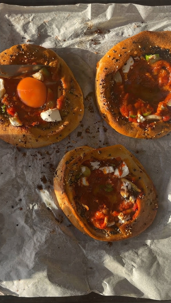Fill pita bowls with sauce and feta. Crack an egg in center well. Bake at 160°C for 4 mins (runny yolk) or 7 mins (set yolk).