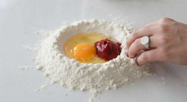 Ensures silky pasta sheet. Mound 300g Tipo 00 flour on a work surface, make a well in the center, and add 3 eggs, salt, and olive oil. Knead for 8–10 minutes until smooth and elastic. Wrap in plastic film and rest at room temperature for 1 hour.